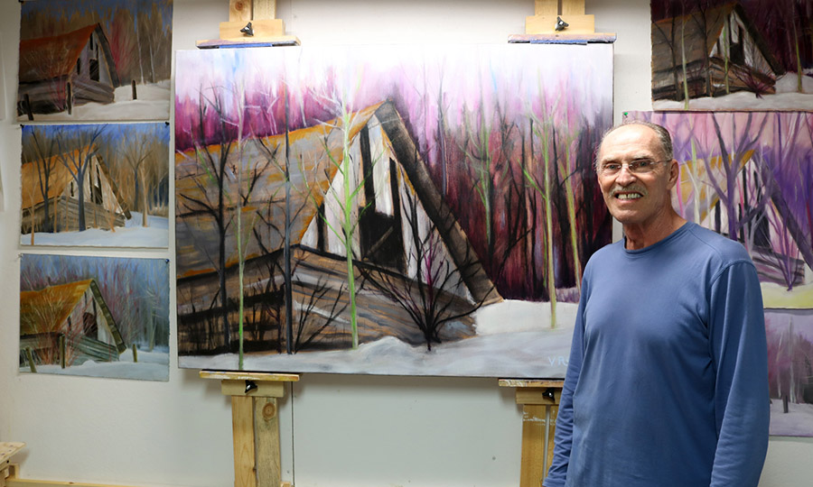 Alex Janvier posing by some of his paintings