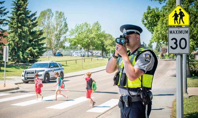 Children in cross walk, officer on side checking vehicle speeds.