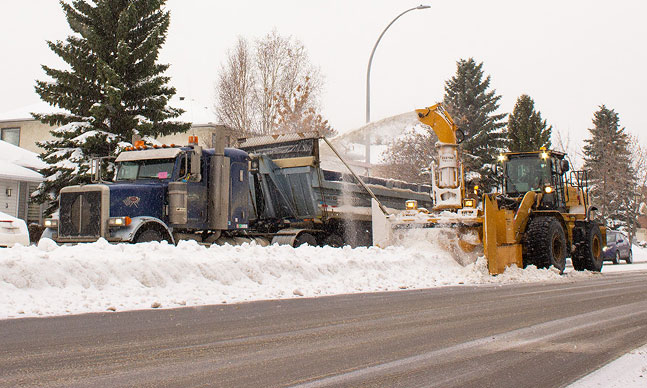 Snow grader blowing snow from windrow into truck