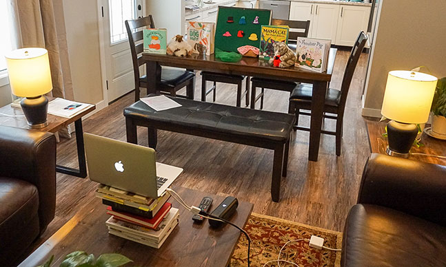 Living room setup with computer on centre table and kids picture books as backstage