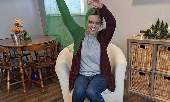 Story-teller holds up green transparent veil