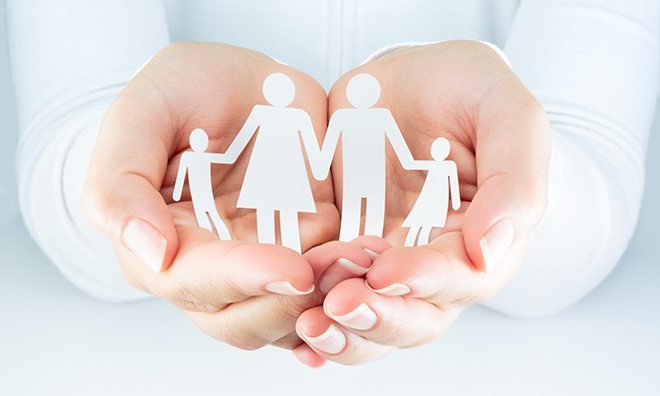 Hands carefully holding paper cut-out of a family