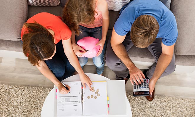 Family on a couch working on their budget and counting money.