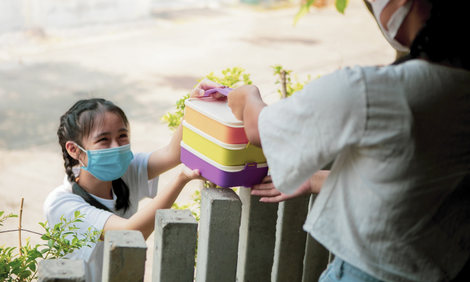 Girl handing box over fence