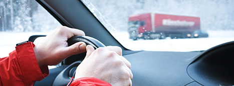 driver clutching steering wheel while driving on a snowy roadway