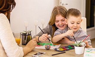 Two kids painting on kitchen table