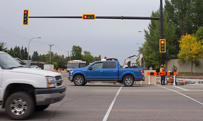 Image showing construction workers working alongside traffic on road.