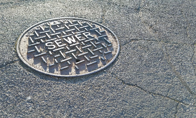 Image of a manhole cover with sewer written on the top